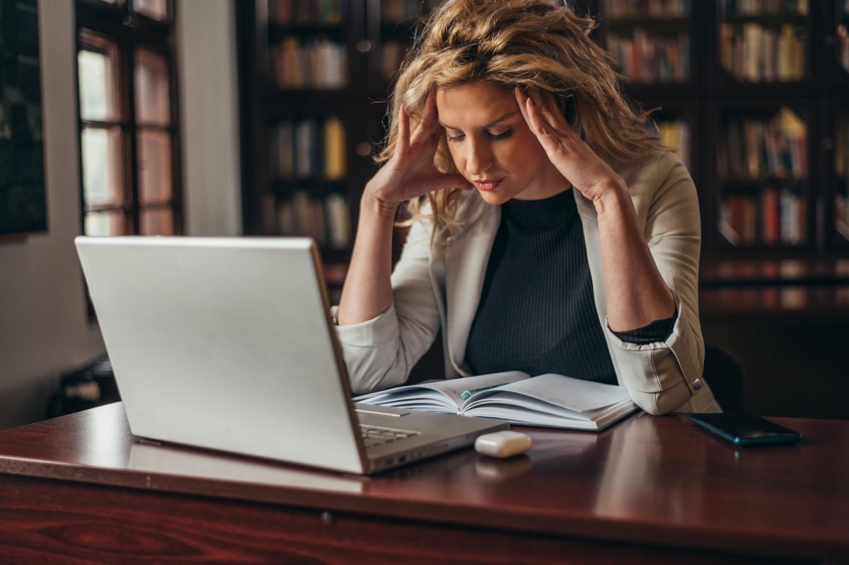 Müde Frau mit Konzentrationsproblemen sitzt vor einem Laptop