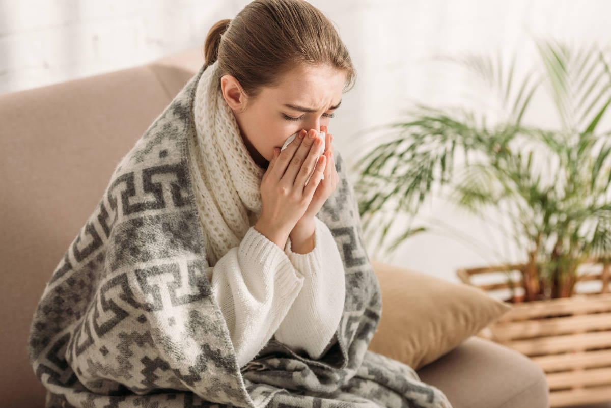 Eine Frau mit Erkältung putzt sich die Nase. Erklärungen und Halsschmerzen sind gute Propolis-Anwendungsgebiete.